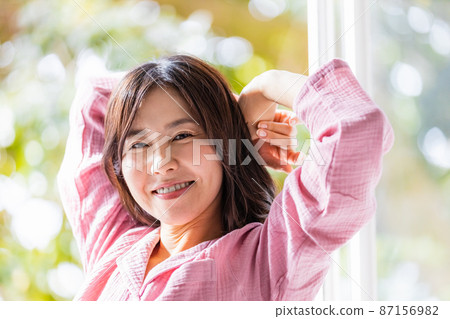 A refreshing woman standing by the window and bathing in the morning light 87156982