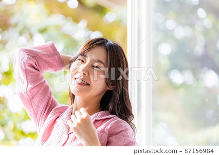 A refreshing woman standing by the window and bathing in the morning light 87156984