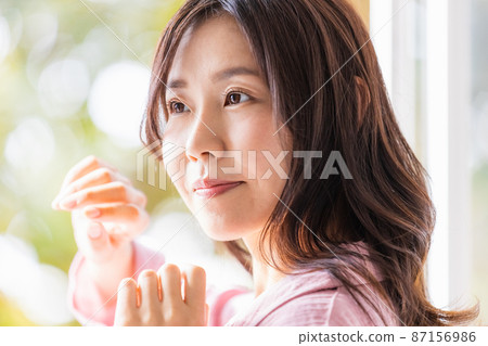 一個清爽的女人站在窗邊沐浴晨光 一個清爽的女人站在窗邊沐浴晨光 87156986
