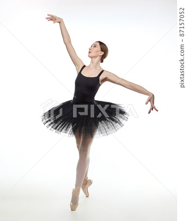 attractive ballerina stands on her fingertips. photo shoot in the studio on a white background attractive ballerina stands on her fingertips. photo shoot in the studio on a white background 87157052