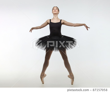 attractive ballerina stands on her fingertips. photo shoot in the studio on a white background 87157058