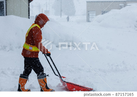 A man who is working on snow gathering in winter Snow scoop 87157165
