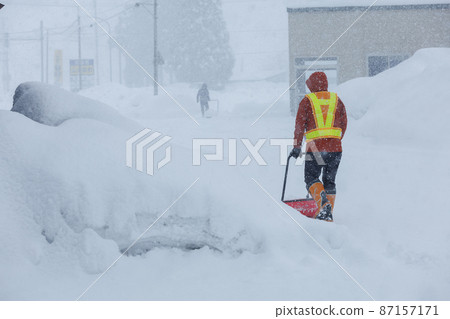 A man who is working on snow gathering in winter Snow scoop A man who is working on snow gathering in winter Snow scoop 87157171