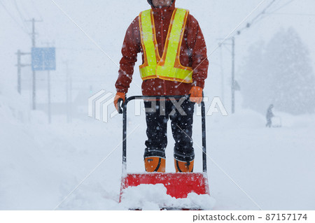 A man who is working on snow gathering in winter Snow scoop A man who is working on snow gathering in winter Snow scoop 87157174