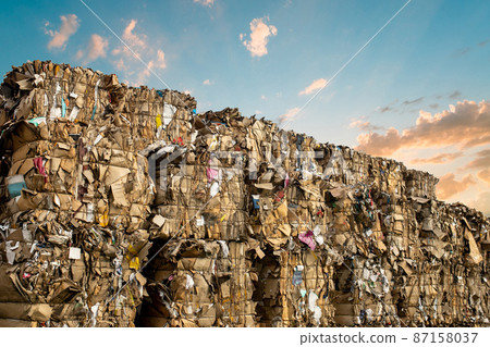 A large stack of waste paper in different colors outdoors against the backdrop of a sunset A large stack of waste paper in different colors outdoors against the backdrop of a sunset 87158037
