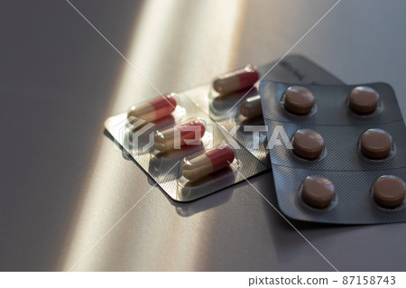 Tablets and capsules placed on a desk by the window Tablets and capsules placed on a desk by the window 87158743