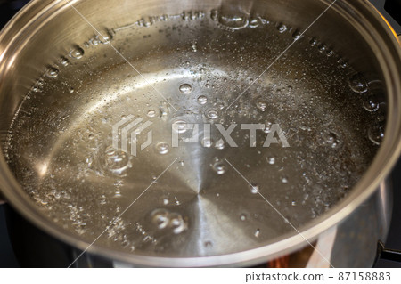 Water that begins to boil in a metal pot Water that begins to boil in a metal pot 87158883