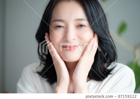 A beautiful Asian (Japanese) woman who smiles because she cares about her skin condition. Close-up, looking at the camera. A beautiful Asian (Japanese) woman who smiles because she cares about her skin condition. Close-up, looking at the camera. 87159122