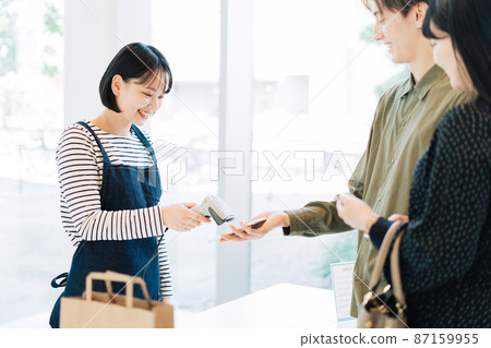 Female clerk processing smartphone payment Female clerk processing smartphone payment 87159955