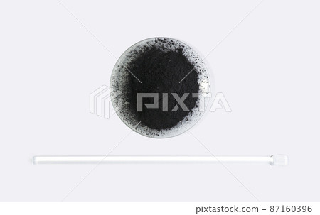 Carbon Charcoal Powder in Chemical Watch Glass placed next to stirring rod. Close up chemical ingredient on white laboratory table. Top View Carbon Charcoal Powder in Chemical Watch Glass placed next to stirring rod. Close up chemical ingredient on white laboratory table. Top View 87160396