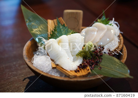 The sashimi set is beautifully arranged in a wooden plate decorated with green bamboo leaf. Japanese Cuisine Buffet. Chef's Choice 87160419