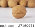 Walnuts on a white background, one nut in the foreground 87160951