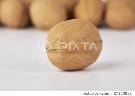Walnuts on a white background, one nut in the foreground 87160951