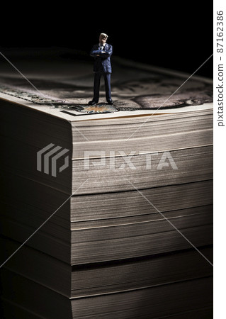 Money (a wad of bills) and a miniature businessman Money (a wad of bills) and a miniature businessman 87162386