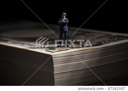 Money (a wad of bills) and a miniature businessman Money (a wad of bills) and a miniature businessman 87162387