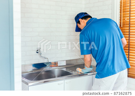 Men in work clothes cleaning the sink 87162875
