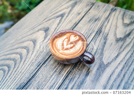 Hot latte art coffee in ceramic cup on wooden table Hot latte art coffee in ceramic cup on wooden table 87163204