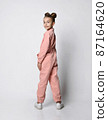 girl in a pink cotton jumpsuit stands with her 87164620