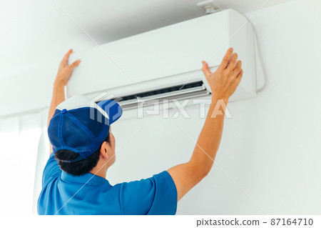 A man in work clothes checking air conditioners and air conditioning equipment 87164710