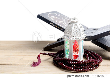 Arabic lamp with colorful light and prayer beads on wooden table 87164808