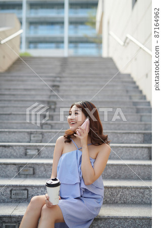 beautiful woman talking on smartphone and holding paper cup beautiful woman talking on smartphone and holding paper cup 87164962