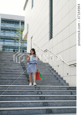 Shopper woman buying online on the smart phone in the street Shopper woman buying online on the smart phone in the street 87164964