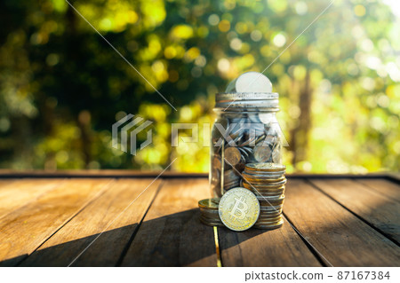 Gold bitcoins placed on a wooden table with natural green background. 87167384