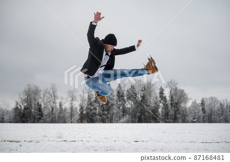 Cheerful young man jumping with joy outside in white snowy nature Cheerful young man jumping with joy outside in white snowy nature 87168481