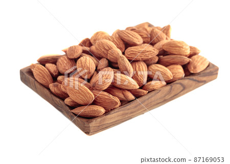 Almond in wooden dish isolated on white. Almond in wooden dish isolated on white. 87169053