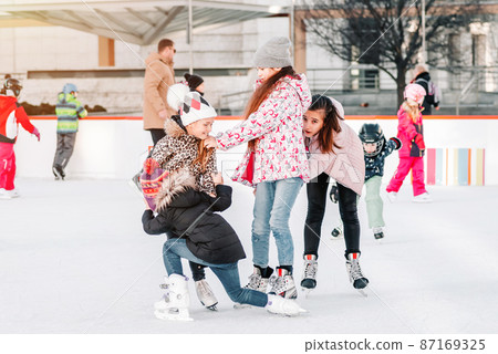 Soft,Selective focus.People, friendship, sport and leisure concept - happy friends on skating rink.Group of teenage friends ice skating on an ice rink.Funny moment fell on the ice skating rink. Soft,Selective focus.People, friendship, sport and leisure concept - happy friends on skating rink.Group of teenage friends ice skating on an ice rink.Funny moment fell on the ice skating rink. 87169325