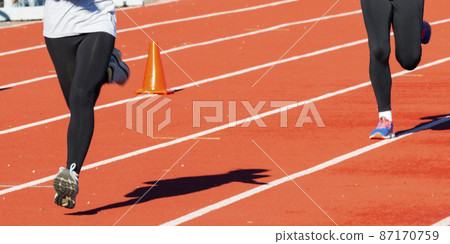 Two runners wearing black spandex running on a track 87170759