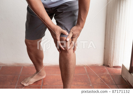 A man supporting herself from numbness, muscle weakness, pain, and tingling in the knee nerve endings. This is a side effect of Guillain-Barre Syndrome after vaccination against COVID-19 87171132