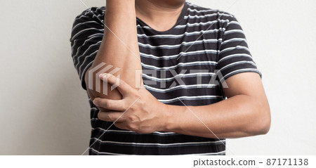Man hand with numbness and pain in the elbow feels sore and tingling due to numbness in the nerve endings, a side effect of Guillain-Barre Syndrome after vaccination against COVID-19 Man hand with numbness and pain in the elbow feels sore and tingling due to numbness in the nerve endings, a side effect of Guillain-Barre Syndrome after vaccination against COVID-19 87171138