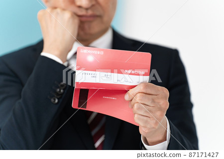 Senior businessman who is worried about looking at his passbook Senior businessman who is worried about looking at his passbook 87171427