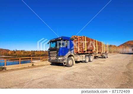 Blue logging truck on forest road in autumn Blue logging truck on forest road in autumn 87172409