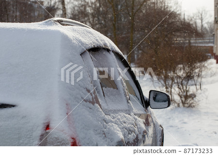 close-up view of car covered with snow and snow drift on its wheel 87173233