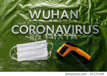 words wuhan coronavirus laid with metal letters on green crumpled plastic film backdrop with face masks and thermometer words wuhan coronavirus laid with metal letters on green crumpled plastic film backdrop with face masks and thermometer 87173395