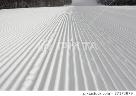 滑雪場菅平高原滑雪場在雪被壓縮的早晨的第一個斜坡上。這是一個包裝精美的冬季景觀。 滑雪場菅平高原滑雪場在雪被壓縮的早晨的第一個斜坡上。這是一個包裝精美的冬季景觀。 87173979