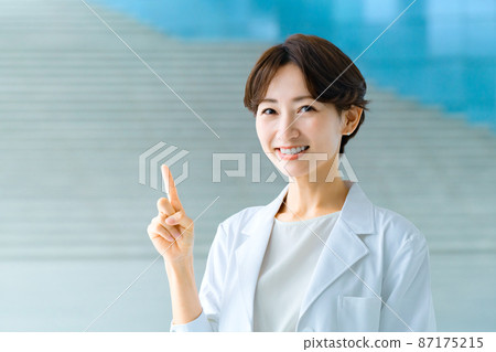 Smiling female doctor in a white coat at the hospital Smiling female doctor in a white coat at the hospital 87175215