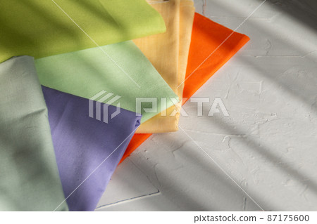 Stack of colorful cotton fabric against grey background, slow fashion and home sewing concept Stack of colorful cotton fabric against grey background, slow fashion and home sewing concept 87175600