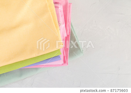 Stack of colorful cotton fabric against grey background, slow fashion and home sewing concept 87175603