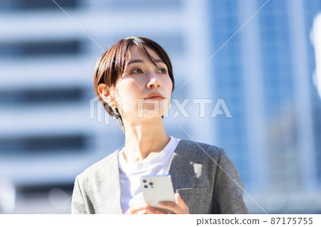 A woman operating a smartphone in the city A woman operating a smartphone in the city 87175755