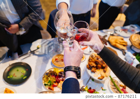 hands with glasses above the festive table 87176211