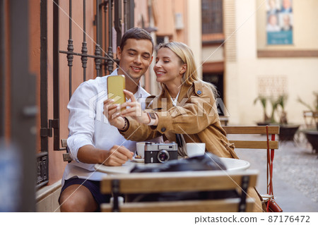 Happy couple taking selfie on smartphone while sitting in cafe 87176472