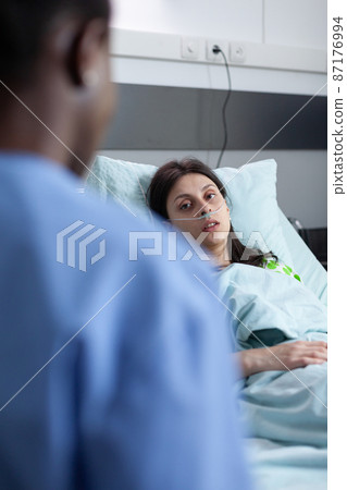 Woman with illness having low spo2 saturation in private hospital ward looking at nurse 87176994