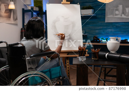 Young illustrator in wheelchair drawing artistic vase ilustration Young illustrator in wheelchair drawing artistic vase ilustration 87176998