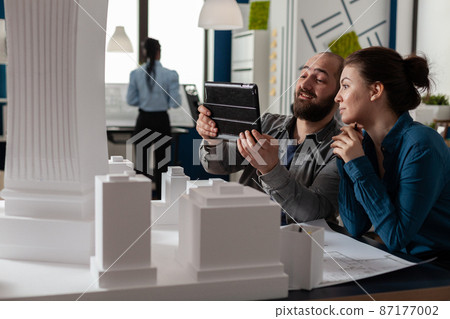 Two architects working together looking at tablet with blueprints Two architects working together looking at tablet with blueprints 87177002