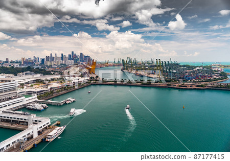 The huge busiest logistic port in Singapore, plenty of cranes to move containers, huge cargo ships in the background, shopping malls and skyscrapers surrounded by, entertainment island nearby The huge busiest logistic port in Singapore, plenty of cranes to move containers, huge cargo ships in the background, shopping malls and skyscrapers surrounded by, entertainment island nearby 87177415