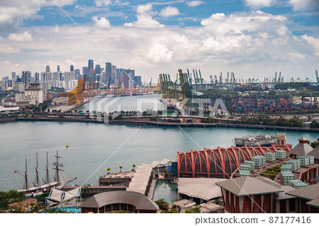 The huge busiest logistic port in Singapore, plenty of cranes to move containers, huge cargo ships in the background, shopping malls and skyscrapers surrounded by, entertainment island nearby The huge busiest logistic port in Singapore, plenty of cranes to move containers, huge cargo ships in the background, shopping malls and skyscrapers surrounded by, entertainment island nearby 87177416