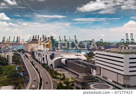 The huge busiest logistic port in Singapore, plenty of cranes to move containers, huge cargo ships in the background, shopping malls and skyscrapers surrounded by, entertainment island nearby The huge busiest logistic port in Singapore, plenty of cranes to move containers, huge cargo ships in the background, shopping malls and skyscrapers surrounded by, entertainment island nearby 87177425